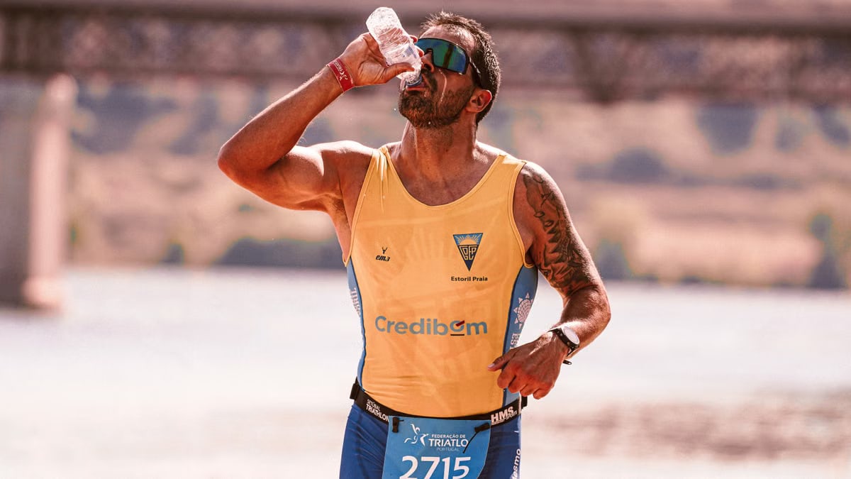 A focused male athlete drinks water while running in a marathon, showcasing endurance.